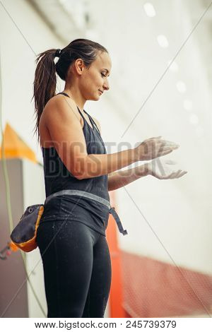 Young Woman In Dark Grey Outfit Coating Her Hands In Powder Chalk Magnesium, Preparing To Workout At