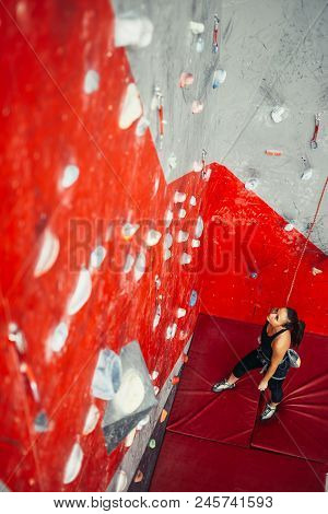 High Angle View Of Sporty Brown-haired Woman Exercising Wall Climbing On Colorful Red Artificial Roc