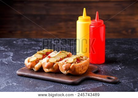 Image Of Hotdogs On Cutting Board At Table With Ketchup And Mustard