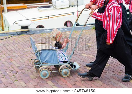 Urk, Netherlands - May 19, 2018: Unknown Baby In A Vintage Stroller In Traditional Costume On The Ur