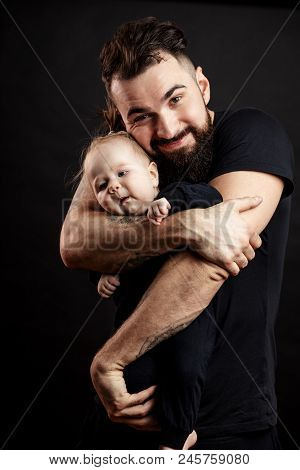 Happy Father And Infant Daughter Posing With Different Grimaces At Studio Black Background Witj Copy