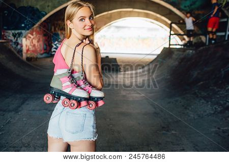 Gorgeous Blonde Girl Is Posing On Camera. She Is Loooking Back On It And Smiling. Girl Is Holding Ro