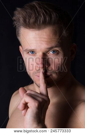 Keep Silence. Attractive Guy. Shhhh. The Man Asks To Keep A Secret. Black Background.