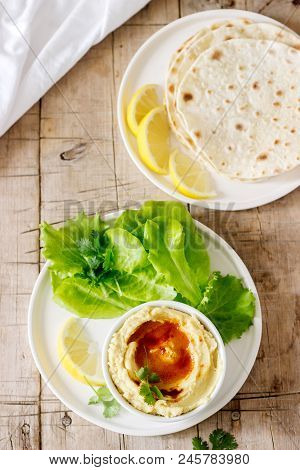Hummus With Olive Oil And Paprika, Served With Pita, Lemon And Lettuce Leaves. Selective Focus.