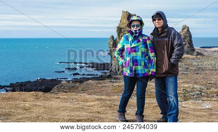 Asian Senior Couple Travel Photo With Iceland Pennisula Rock Landmark