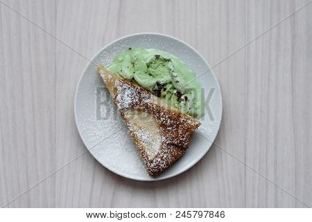 A Slice Of Apple Pie With Pistachio Ice Cream On A Wooden Background In A White Plate.