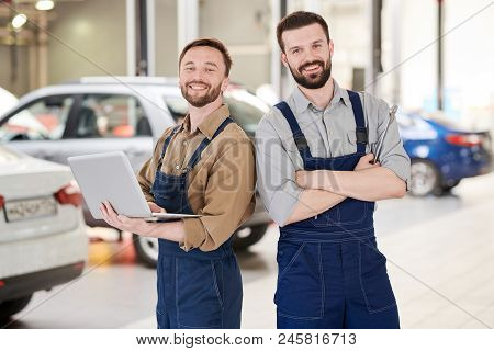 Waist Up Portrait Of Two Handsome Bearded Workers Smiling At Camera While Posing  In Production Work