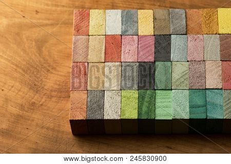 Abstract back ground, consisting of hand painted colored wooden cubes on grungy wooden desk. Warm earth colors or neutral colors. grey pale pink, green, beige.