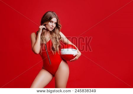 Pretty Bikini Model Holding Red Ball In Studio On Red Background