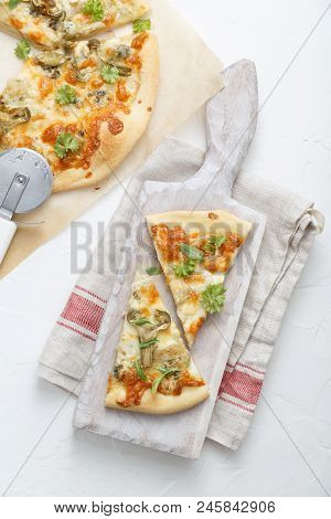 Two Pieces Of Pizza With Artichoke On White Cutting Board, Top View