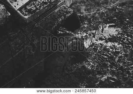 Off-road. Fragment Of Car Stuck In Dirt, Close Up. Wheel In Deep Puddle Of Mud Overcomes Obstacles. 