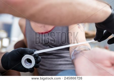 Close-up of the wrapped forearm of a young woman after getting a new cool tattoo in a modern studio with sterile safety supplies