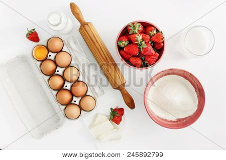 Flat Lay Set Raw Ingredients For Cooking Strawberry Pie Or Cake On White Background. Eggs, Flour, Mi