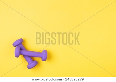 Two Violet Dumbbells On Yellow Background. Top View, Copy Space.
