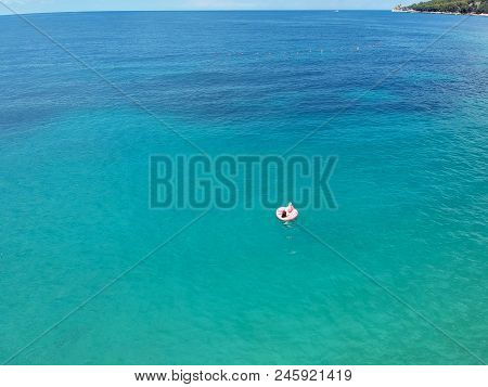 Aerial View Young Woman On Giant Inflated Flamingo Float In Turquois Water Of Ionian Sea Albania.