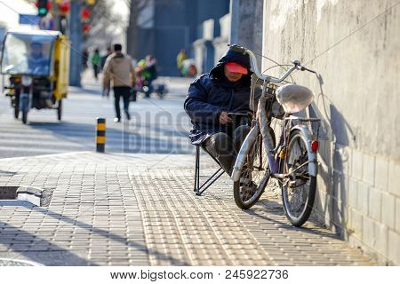 Beijing, China - March 10, 2016: On The Chair, On The Street, Sit On The Man And Watch On A Tablet.