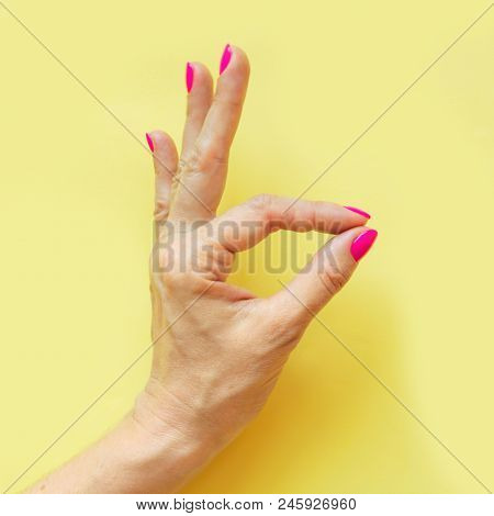 Female Hand With Pink Nail On Yellow. Concept.