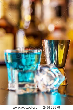 Popular Blue Drink Shot Kamikaze On The Background Of The Bar With Bottles, A Refreshing Drink