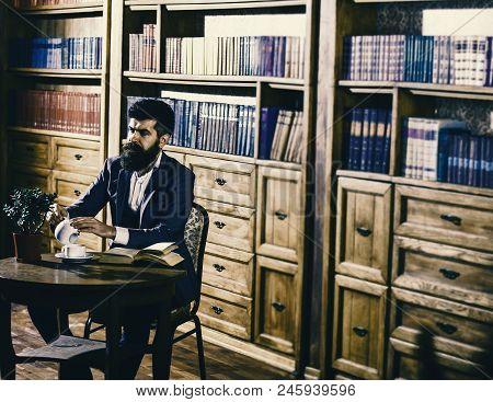 Aristocratic Lifestyle Concept. Man In Classic Suit Sits In Vintage Interior, Library, Book Shelves 