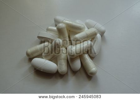 Fistful Of White Capsules Of Magnesium Citrate And Caplets Of Calcium Citrate