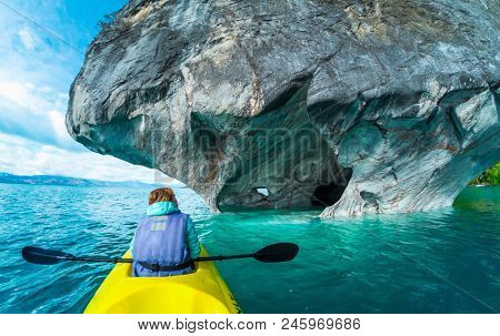 Woman sits in kayak and explores the Marble Caves and rocks on the lake of General Carrera, Chile