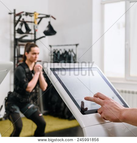Coach Pushing On Screen On Ems Machine While Woman Waiting For Training, Focus Is On Fingers