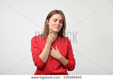 Unhappy Caucasian Woman In Red Pulover Suffering From Throat Pain At Home. Concept Of Being Ill And 