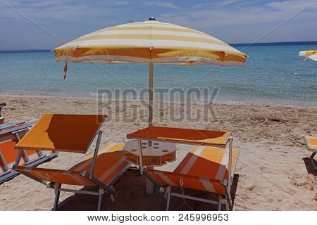 Beach Equipment, Chairs And Sun Umbrella On White Sandy Beach With Light Blue Sea Water, Beach Vacat