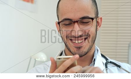 Medical Worker Checking His Phone And Laughing. Close Up Shot