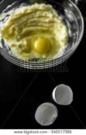 Homemade Cakes, Pastry And Pie Dough Made From Sugar, Butter And Raw Egg. Eggshell On A Black Backgr