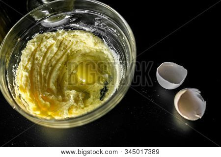 Homemade Cakes, Pastry And Pie Dough Made From Sugar, Butter And Raw Egg. Eggshell On A Black Backgr