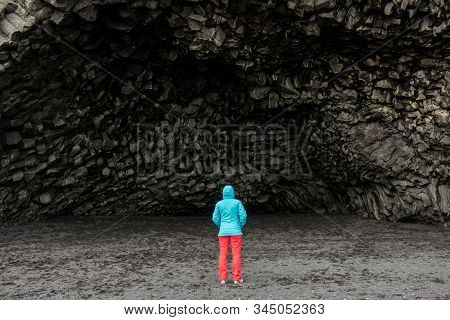 Tourist Woman Admiring The Halsanefshellir Cave Formed In Black Basalt Formation In Vik, Iceland