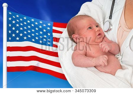Birth Rate In United States Of America. Newborn Baby In Hands Of Doctor On National Flag Background.