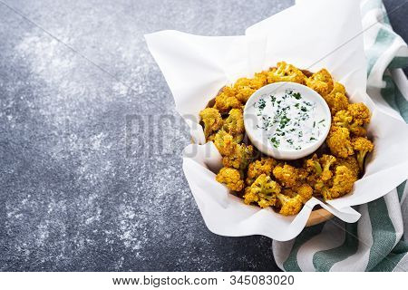 Cauliflower In White Parchment Paper With White Sauce On Gray Background. Healthy Garnish Concept