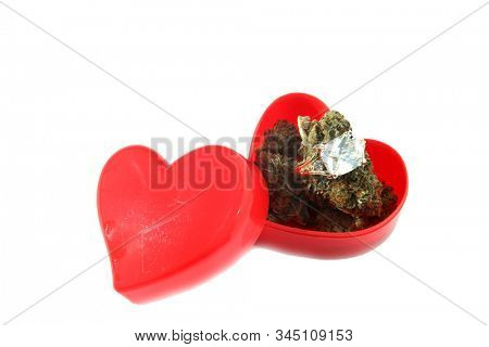 Wedding or Engagement Ring with Marijuana in a Heart Shaped Ring Box. Isolated on white. Room for text. Some people love Cannabis and Diamond Rings. Cannabis Weddings are a new trend in the USA. 