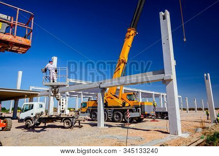 Mobile Crane Is Operating And Worker Is Assembly Concrete Joist In High Place. Height Worker Is Plac