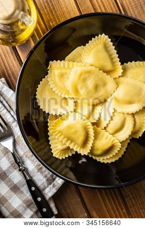Italian stuffed pasta. Panzerotti pasta in bowl on old kitchen table. Flat lay.