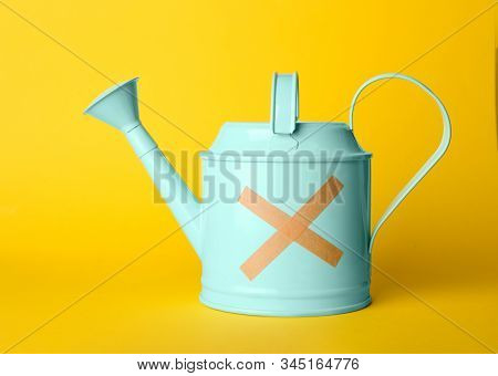Light Blue Watering Can With Sticking Plasters On Yellow Background