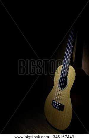 Standing Against The Wall In The Dark Guitar On Which The Light Falls