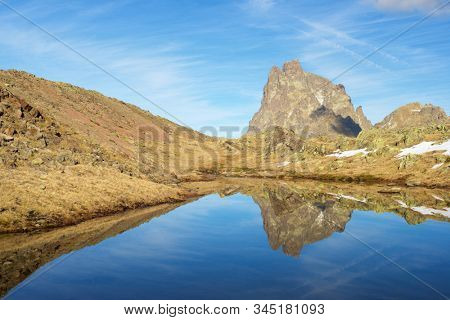 Midi Dossau Peak reflected in a lake. Ossau Valley, Pyrenees National Park, Pyrenees, France.