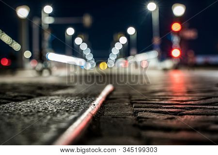 Blurred Background Of A Bridge And Sharpness In Paving Of A Shopping City With Bokeh City Lights