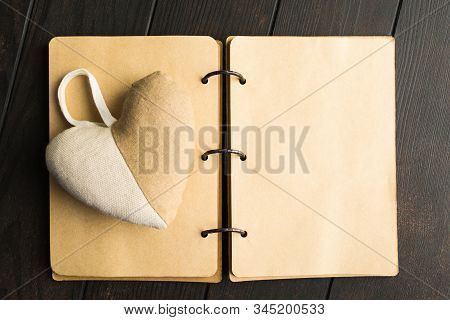 Ol Open Craft Notebook With Hadmade Fluffy Heart Over Brown Wooden Background With Copy Space. Flat 