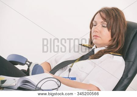 Overworked woman pilot wearing uniform with epaulettes resting or sleeping in briefing room