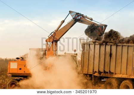 Excavator Loads Manure Into A Tractor With A Trailer In Cold Day. Late Fall. Animal Husbandry And Fa