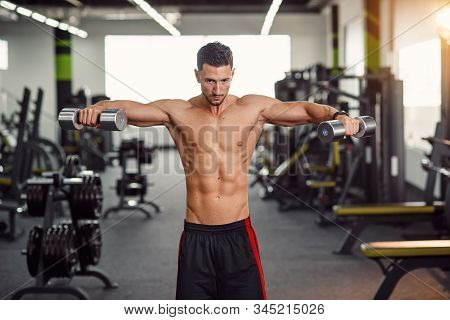 Strong Man Training His Shoulders In The Gym. Isolated Exercise For Training Deltoid Muscle. Work Ou