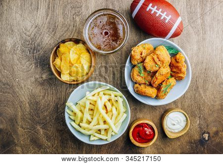 Table Fof Tasty Snacks And Beer Prepared For Watching Sports On Tv. Wooden Background. Top View. Fla
