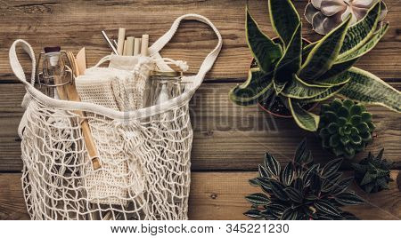 Collection of various succulent plants and Mesh market bag with bamboo cutlery, reusable bottles and eco cotton bags on wooden background
