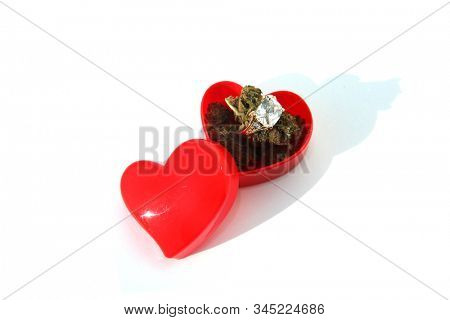 Wedding or Engagement Ring with Marijuana in a Heart Shaped Ring Box. Isolated on white. Room for text. Some people love Cannabis and Diamond Rings. Cannabis Weddings are a new trend in the USA. 
