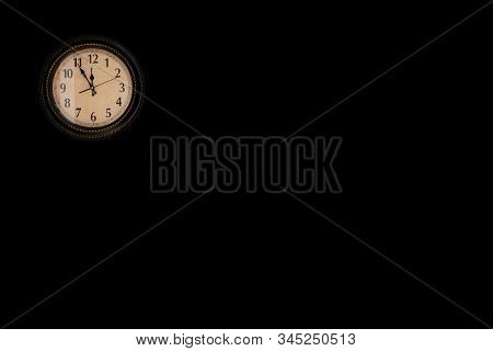 Vintage Wall Clock With Black Clock Hands Is Hanging On Black Wall, Retro Concept, Enoung Space For 