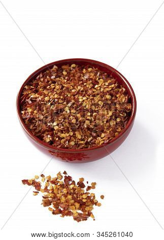 Over Head Shpt Of Hot Chilli Flakes In A Red Colored Bowl  Isolated On A  White Background